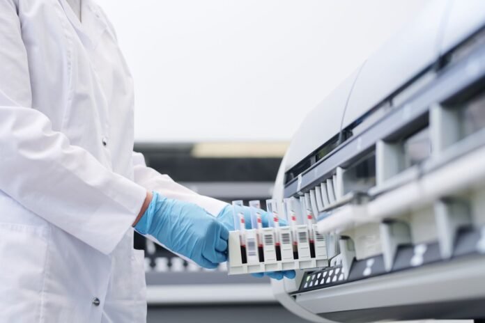 Operatore sanitario con camice e guanti in un locale della farmacia